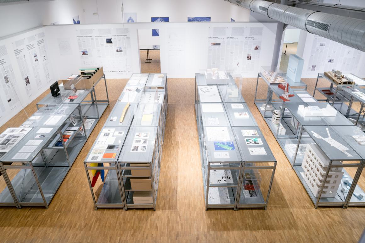 tentoonstellingszicht met 4 grote tafels waarop maquettes en afbeeldingen zijn uitgestald<br>	