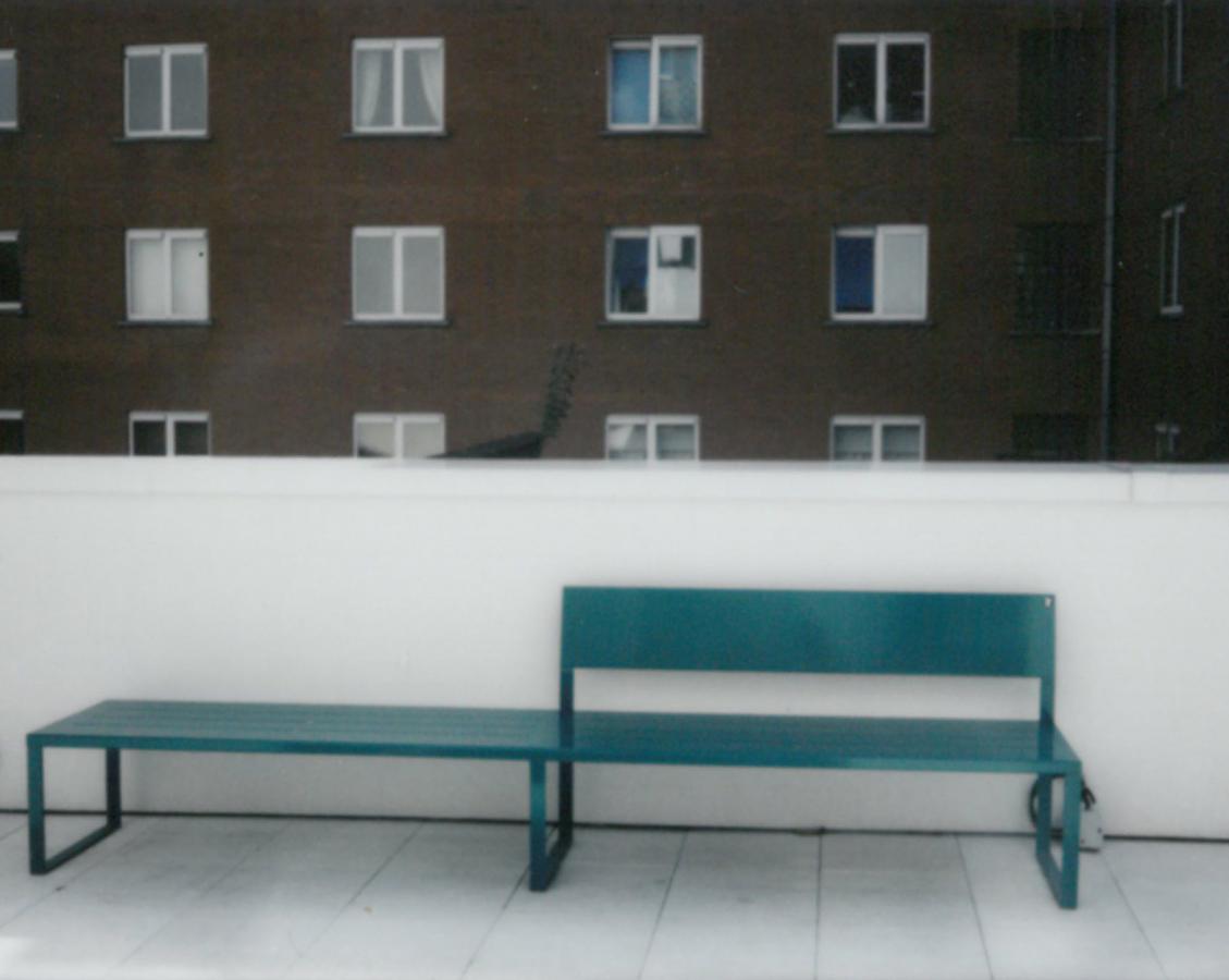 foto van een groene bank in een verstedelijkte buitenruimte<br>	